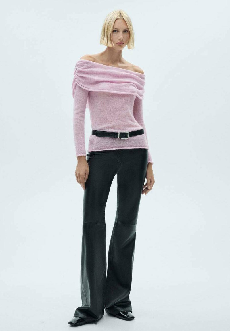 Ljusrosa off-the-shoulder tröja med draperat tyg, kombinerad med svarta vida byxor och ett svart bälte med silverspänne. Slät textur.