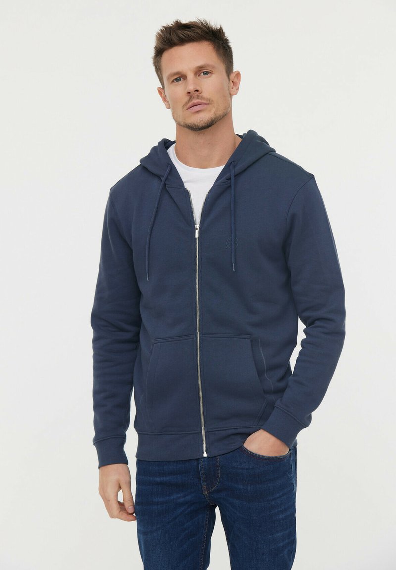 Hoodie zippé bleu marine pour homme fabriqué en tissu doux, avec une poche frontale, une capuche à cordon de serrage et des poignets côtelés.
