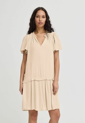 Robe beige courte avec un décolleté en V, des manches courtes bouffantes et un ourlet à volants. Fabriquée en tissu léger avec une surface texturée.