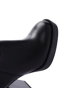 Black leather ankle boot with a sleek design, rounded toe, and a rubber sole. Visible stitching accents along the edges.