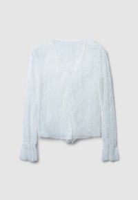 Camicia bianca in pizzo con scollo a V, maniche lunghe e polsini arricciati. Presenta un delicato motivo floreale e una chiusura a cravatta frontale.