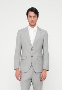 Casaco de fato cinza com lapelas em bico e dois botões. Tecido texturizado, bolso no peito único e dois bolsos frontais com abas.