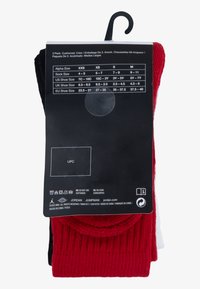 Confezione da tre paia di calzini alla caviglia in nero, rosso e bianco. Il materiale è un morbido tessuto a maglia con texture. La confezione include la tabella delle taglie e le istruzioni per la cura.