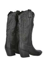 Botas de vaquero de cuero negro con diseños de alas en relieve, acentos de tachuelas, puntas afiladas y tacones de bloque de altura media. Cuenta con una cremallera lateral.