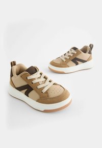 Baskets marron et beige avec un mélange de cuir lisse et de daim, présentant des accents contrastants, des lacets clairs et des semelles en caoutchouc blanc.
