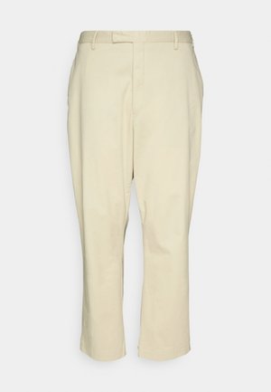 Beige bomullsbukser med rett snitt, med glidelås, to frontlommer og en ren finish uten mønstre eller synlig hardware.