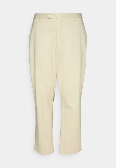 Bež pamuk hlače ravnog kroja, s patentnim zatvaračem, dva prednja džepa i čistim završetkom bez uzoraka ili vidljivih metalnih dijelova.