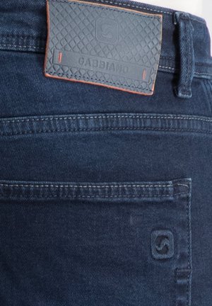Dunkelblaue Jeans aus Denim mit einer aufgenähten Gesäßtasche und einem rechteckigen Lederetikett mit strukturiertem Muster am Bund.