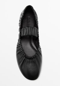 Schwarzer Ballettflachschuh aus Leder mit abgerundetem Zehenbereich, gerafftem Obermaterial und einem elastischen Riemen über dem Spann für zusätzlichen Halt.