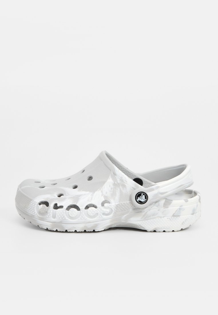 Weiße Crocs-Clogs mit Perforationen, einer runden Form, einem Rückenriemen und einer strukturierten Oberfläche, die ein Logo an der Seite trägt.