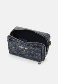 Navy handtas met rits en geometrisch patroon; beschikt over gouden accenten en een enkele compartiment met een donkere, gestructureerde binnenkant.