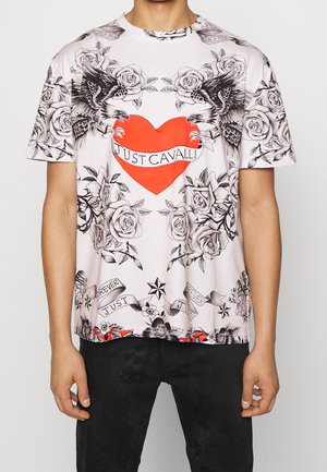 T-Shirt mit schwarz-weißen Rosen, zwei Adlern, einem roten Herzen mit "Just Cavalli" und Bandern mit Text auf dem Oberkörper einer Person.