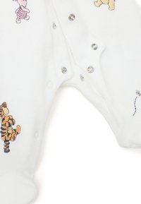 Tutina bianca in morbido tessuto, con personaggi ricamati: Winnie the Pooh, Tigger e un fiore. Chiusura con bottoni a pressione argentati.