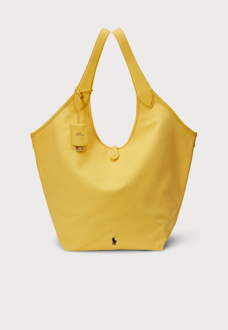 Yellow canvas tote bag with textured shoulder straps, large opening, and an attached small tag. Features a small logo at the base.
