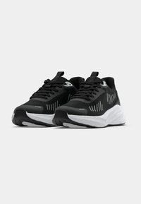 Baskets de sport légères noires avec semelles blanches et bandes verticales réfléchissantes, positionnées côte à côte sur un fond uni.