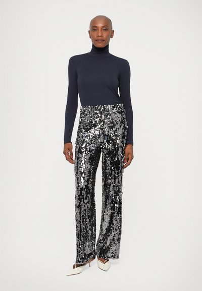 Cămașă cu guler înalt de culoare bleumarin, însoțită de pantaloni evazați cu talie înaltă, cu paiete negre și argintii. Siluetă mulată și elegantă, cu o textură strălucitoare.