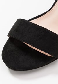 Svart mocka slide sandal med ett brett band över ovandelen och en slät, nude-färgad innersula. Strukturerad ytfinish med rund tåform.