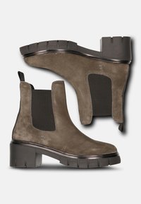 Bruna mocka ankelstövlar med elastiska sidopaneler, platt gummisula och en något kraftigare klack. Texturerat ovandel med minimal sömdetalj.