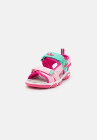 Roza in turkizna sandal z nastavljivimi trakovi, odprtim prstom in teksturirano podplato. Ima vzorčasto notranjost in zanko na peti za enostavno obuvanje.