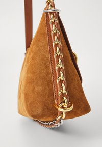 Geantă triangulară din suede maro cu o curea din piele împletită. Prezintă accente din lanț de culoare aurie și o textura netedă.