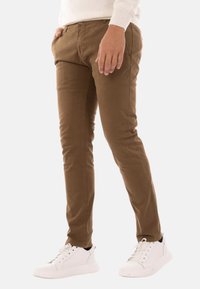 Chinos marroni slim-fit realizzati in cotone, con tasche laterali e una finitura testurizzata, abbinati a sneakers bianche in pelle.