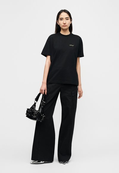 Μαύρο βαμβακερό μπλουζάκι με κοντά μανίκια και μικρό πράσινο λογότυπο. Συνδυάζεται με ψηλόμεσα μαύρα παντελόνια και μικρό μαύρο τσαντάκι.