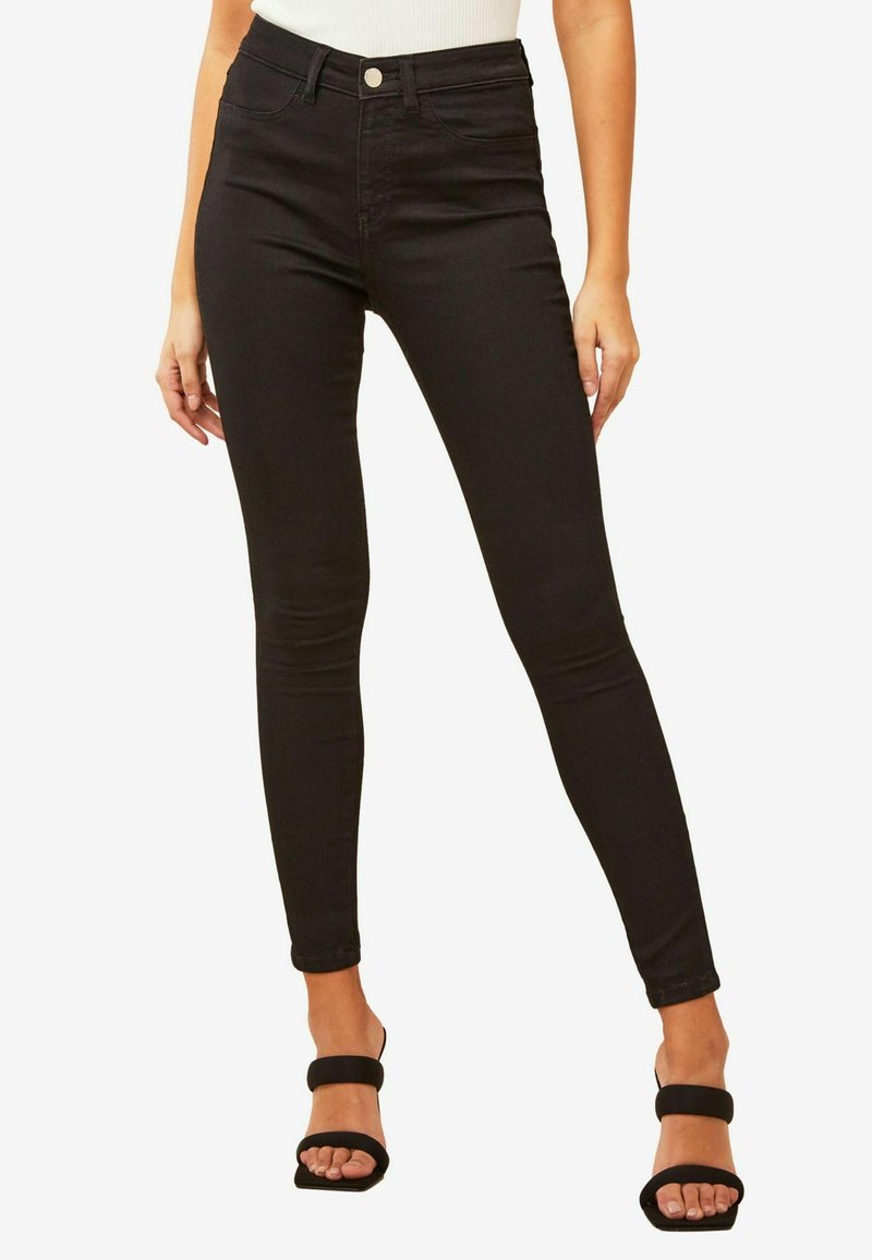 Fekete, magas derekú skinny farmernadrág, rugalmas denim anyagból, elülső gombos zárással és oldalsó zsebekkel, sima textúrával.