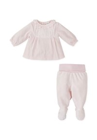 Conjunto de bebé de dos piezas en un suave color rosa. Camiseta de manga larga con cuello con volantes y panel a rayas. Pantalones a juego con diseño con pies y cintura elástica.