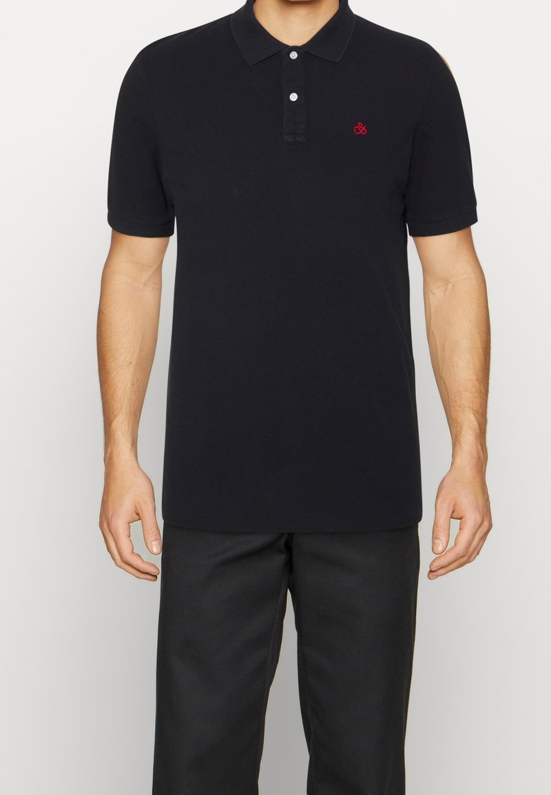 Polo shirt bleu marine avec un col, des manches courtes, une patte de boutonnage à trois boutons et un accent de logo rouge sur la poitrine. Fabriqué en tissu coton doux.