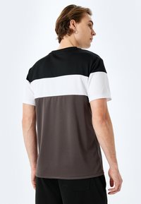 Värgblockerad t-shirt med svarta, vita och grå paneler. Kort ärm, rund halsringning, slät textur och avslappnad passform.