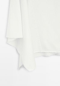 White fabric with unfinished, frayed edges hanging against a plain white background.