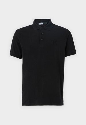 Sort polo-shirt lavet af blød bomuld. Har krave, tre-knaps placket og et broderet "K" logo på venstre bryst. Korte ærmer.