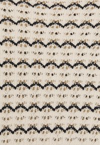 Modèle au crochet mettant en vedette un fil de couleur crème avec des accents en noir en forme de vagues. Le design présente des sections ajourées et un aspect texturé et tissé.