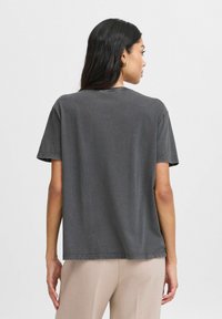Mørkegrå bomulds t-shirt med en afslappet pasform, korte ærmer og rund hals. Har minimalistisk syning langs kanten.