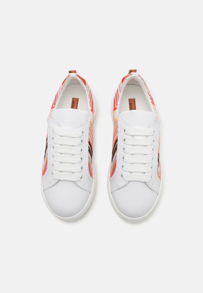 Baskets blanches avec un motif zigzag multicolore sur les côtés, texture lisse, bout arrondi et laçage à six œillets.