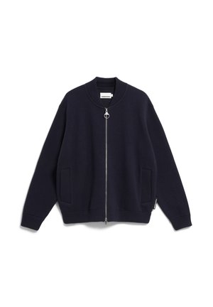 Marineblauwe zip-up trui met een geribde kraag, manchetten en zoom. Beschikt over twee voorzakken en een zilveren ronde ritssluiting. Zachte textuur.