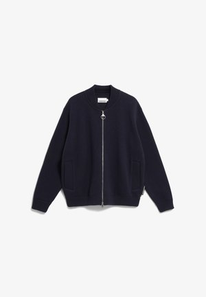 Marineblauwe zip-up trui met een geribde kraag, manchetten en zoom. Beschikt over twee voorzakken en een zilveren ronde ritssluiting. Zachte textuur.