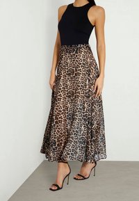 Body nero senza maniche abbinato a una gonna maxi fluida con stampa leopardata in tonalità marrone e nera. Sandali neri con tacco alto e cinturini completano l'outfit.