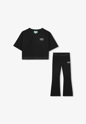 Ensemble t-shirt noir court et leggings évasés. Fabriqué en matériau doux ; présente des patches de logo et des ceintures élastiques avec des détails de marque.