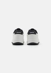 Vita sneakers med svarta accenter, med en texturerad ovandel, rund tå och synlig varumärkeslogga på baksidan. Gummisula med greppmönster.