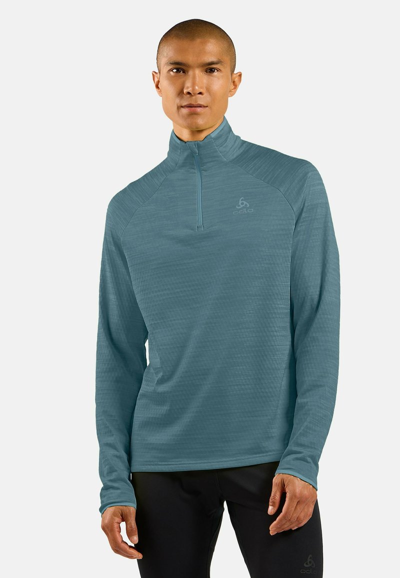 Helles blaues Langarmshirt mit einem Viertelreißverschlusskragen, strukturiertem Stoff und Logo auf der Brust. Entworfen für aktive Freizeit.