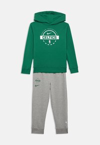 Sweatshirt verde com os logótipos dos Boston Celtics e da Nike, combinado com calças de fato cinzentas com os logótipos dos Celtics, da Nike e do emblema da NBA na perna.