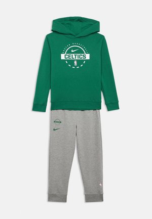 Hoodie vert avec les logos des Boston Celtics et de Nike associé à un pantalon de survêtement gris portant les logos des Celtics, de Nike, et l'emblème de la NBA sur la jambe.