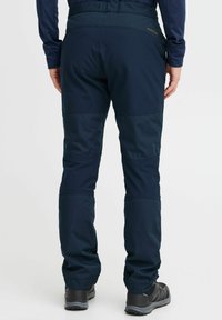 Pantaloni de exterior navy, confecționați dintr-un material rezistent, cu talie ajustată, panouri la genunchi și fermoare la glezne. Asortați cu încălțăminte de drumeție negre.