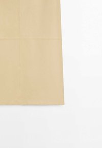 Jupe en cuir beige avec coutures visibles, présentée de côté sur fond blanc. Aucune personne ni objet supplémentaire visible.