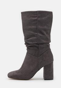 Botte grise en daim, haute jusqu'au genou, au design décontracté, avec un bout pointu et un talon épais solide, mettant en valeur une texture lisse et des coutures soignées.