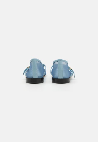 Vista traseira de sapatos planos em azul claro, feitos de um material texturizado, com um pequeno salto e duas tiras com um detalhe de fivela dourada.