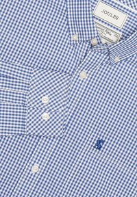 Chemise à manches longues à carreaux vichy bleu et blanc avec col boutonné et petit logo brodé sur la poche poitrine.