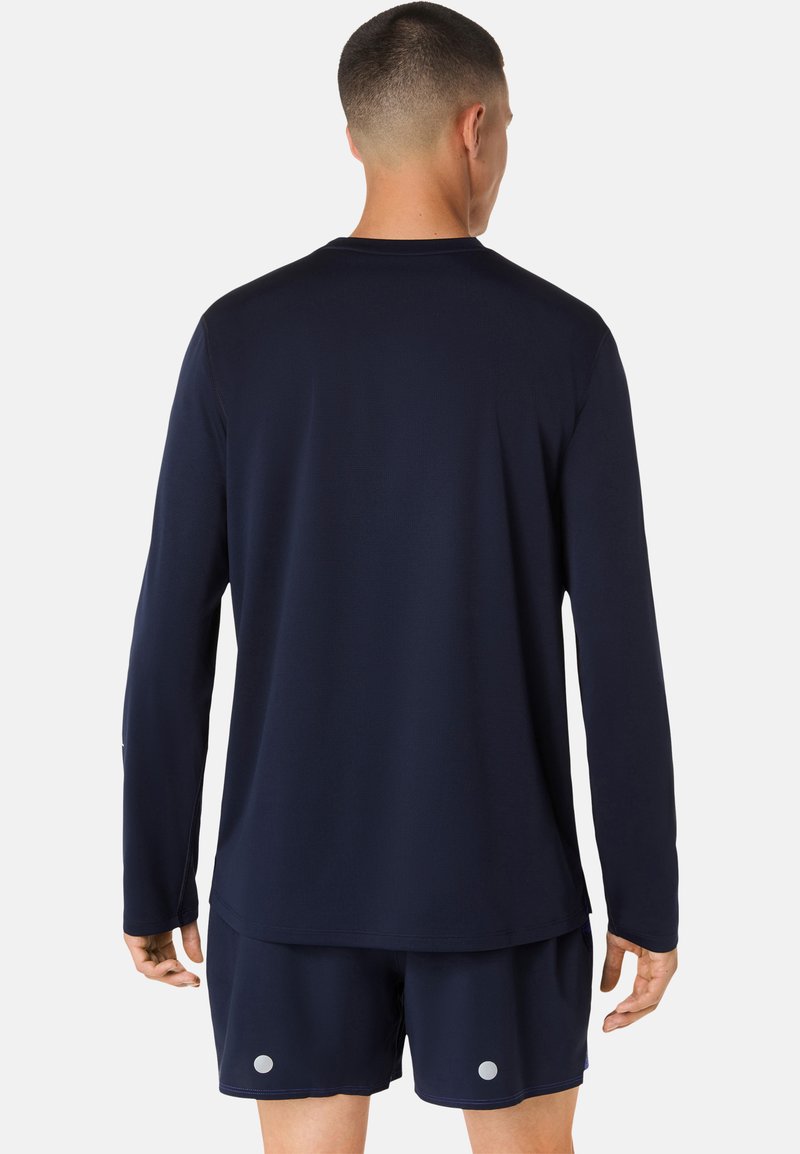 Chemise de sport à manches longues bleu marine en tissu léger, avec une coupe décontractée et des coutures plates pour plus de confort. Détail logo visible sur la manche.