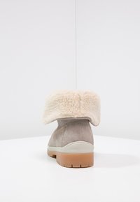 Szary zamszowy but z kremowym kołnierzem z fałszywego futra, który można złożyć oraz z teksturowaną gumową podeszwą. Minimalistyczny design z detalem przeszyć po bokach.